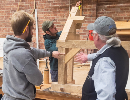 Restoration workers inspecting building frame construction inside a workshop