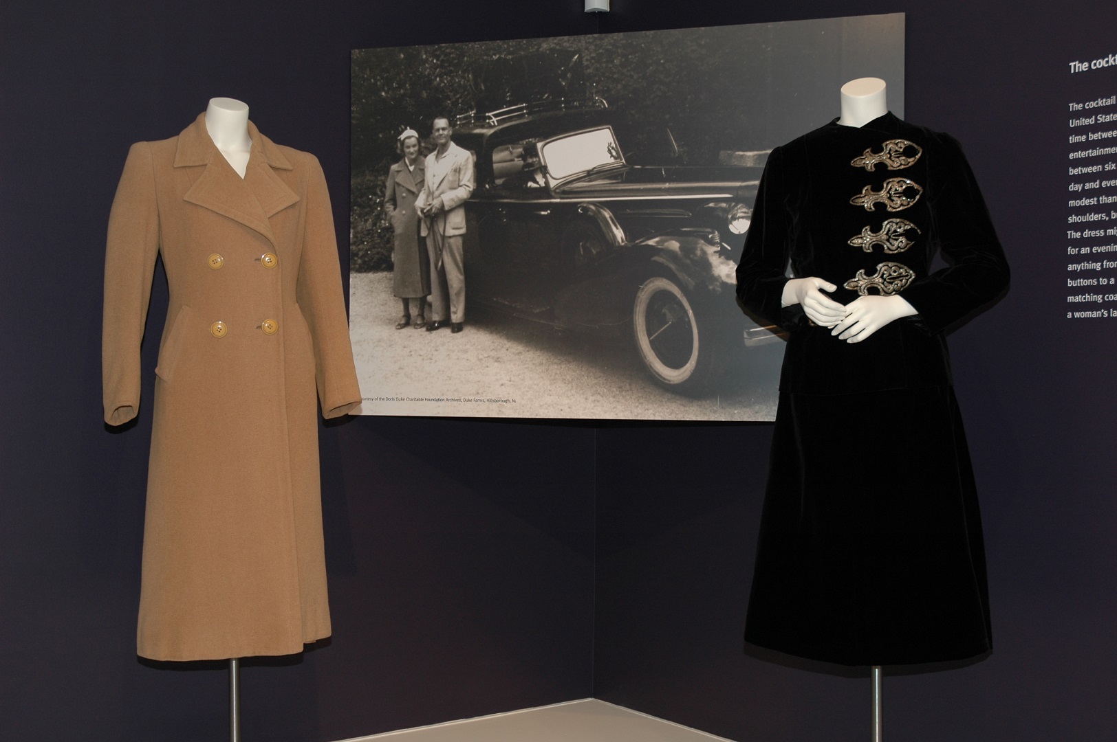 Display of two coats in front of a black and white photograph of Doris, outside in a coat